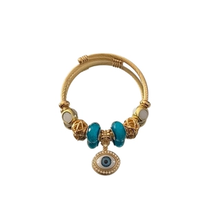 Gold twist rope open bangle featuring evil eye pendant with blue glass and pearl beads