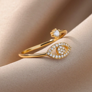 Close-up of golden evil eye ring with micro-pave zircons on luxury champagne silk