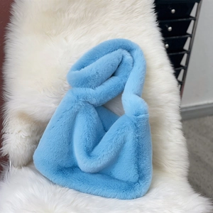 Macro view of blue faux fur plush shoulder bag with soft texture on white furry rug