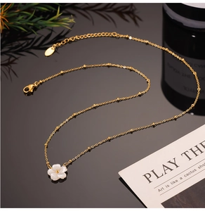 Detail of elegant 18K gold-plated chain with shell flower pendant and lobster clasp