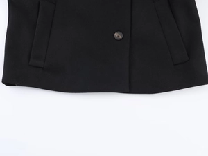 Detail view of black wool jacket showing marble-textured button and neat hem stitching