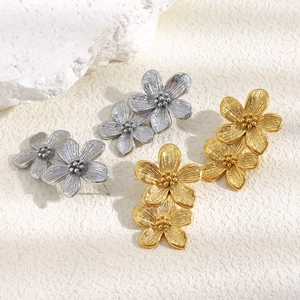 Detailed view of vintage gold and silver layered flower earrings on a white stone prop