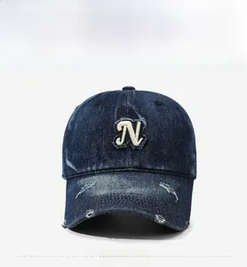 Detail of vintage denim baseball cap with white N letter embroidery and distressed brim