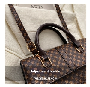 Close-up of adjustable gold buckle and floral texture on brown faux leather bag