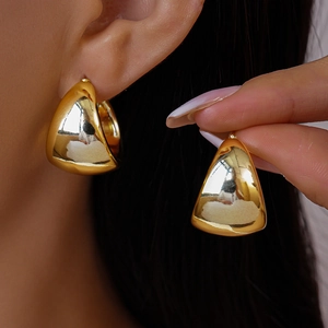 Close-up of chunky gold triangular earrings with polished mirror finish on model