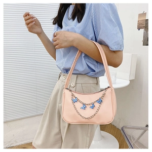 Pink shoulder bag with silver chain and blue butterfly charms worn by a model