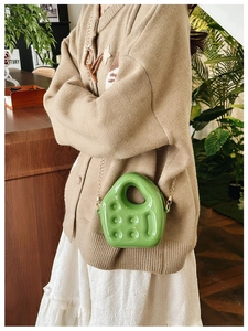 Close-up of green PVC mini jelly bag with unique house shape and golden chain strap
