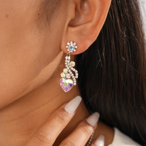Détail de boucles d'oreilles cœur en cristal et fleurs portées par un mannequin