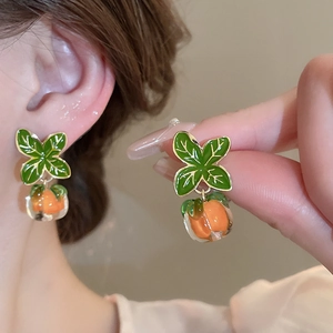 Detail of colorful floral earrings with green leaves and orange fruit resin pendants