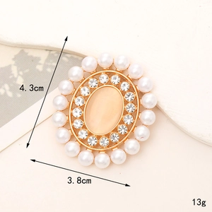 Oval gold brooch with white pearls, clear rhinestones, and peach opal stone centerpiece