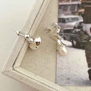 Macro detail of silver pearl earrings on artistic cream canvas with vintage photo