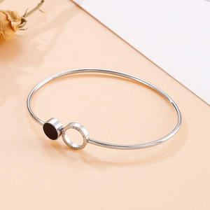 Silver open bangle with black resin charm and LOVE YOU engraved ring on peach background