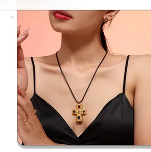 Detail of vintage 18K gold plated cross pendant with multicolored gems on a black cord