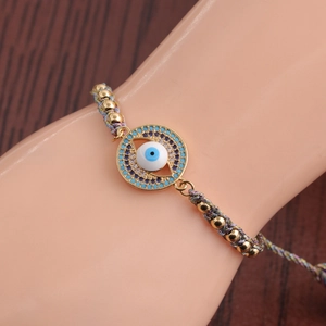 Close-up of a woven Evil Eye bracelet with gold beads and sparkling cubic zirconia stones