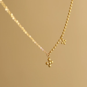 Macro detail of gold 18K plated titanium steel chain with beaded cross pendants