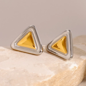 Makroaufnahme von zweifarbigen Gold- und Silber-Dreiecks-Ohrsteckern auf einem Naturstein