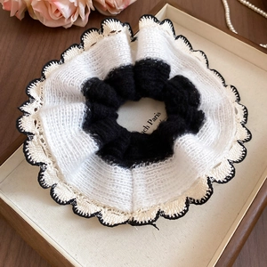Detail of a black and white crochet lace scrunchie with knit mesh edge on a tray