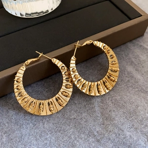 Detailed view of large gold-plated twisted hoop earrings with intricate woven texture