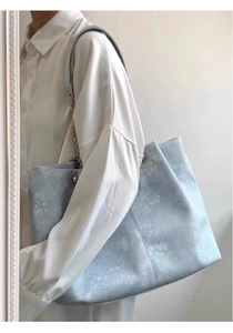 Spacious light blue tote bag with floral patterns shown on a model for daily use