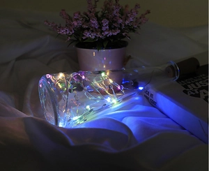 Close-up of multicolor LED copper wire cork lights inside a clear glass bottle for decor