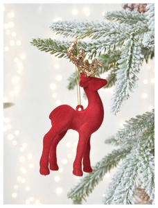 Close-up of red flocked reindeer ornament with golden glitter antlers on a snowy branch