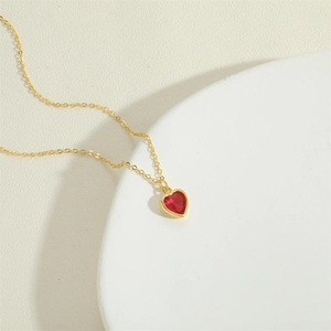Detail of red heart zircon pendant with golden border on a fine gold O-chain necklace