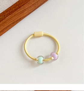 Dettaglio di elastico giallo per capelli con perline macaron per coda di cavallo