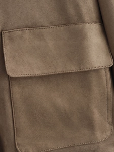 Detailed macro view of the brown suede jacket featuring a flap pocket and stitching
