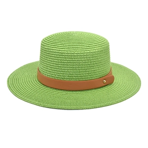 Close-up of light green straw boater hat featuring a brown leather band with gold rivets
