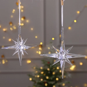 Set of two crystal acrylic snowflake ornaments hanging on a festive Christmas tree