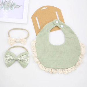 Flat lay of bean green cotton baby bib with lace trim and matching headband set