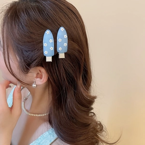 Close-up of elegant light blue duckbill hair clips with white daisy patterns on hair
