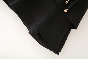 Détail du tissu crêpe noir avec cordons décoratifs à boules métalliques dorées