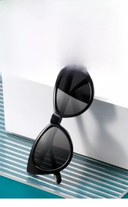 Detail view of stylish black cat eye sunglasses on a white geometric block with blue background