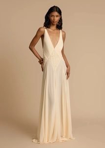 Detail of elegant cream maxi dress featuring deep V-neckline and intricate lace patchwork