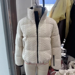 White cable-knit ski jacket with stand collar and black zipper detail on mannequin