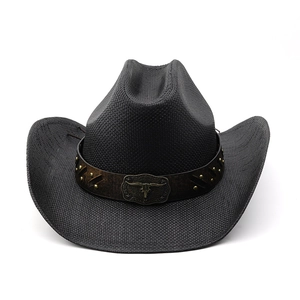 Close-up of black straw cowboy hat with brown leather band and golden longhorn metal detail