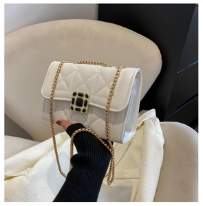 Close-up of white quilted leather flap bag with elegant gold chain shoulder strap