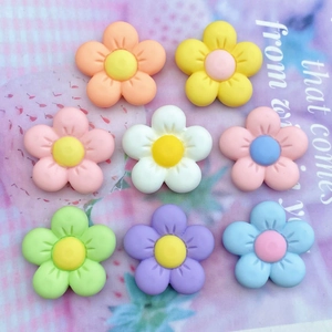 Flat lay of colorful matte five-petal resin flowers for DIY crafts and phone case decor