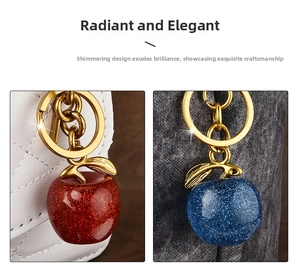Sparkling resin apple keychain with gold metal ring on leather bag and denim