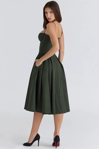 Side view of dark green backless camisole dress with pleated A-line skirt and thin straps