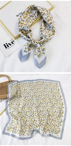 Detail of yellow floral silk scarf tied elegantly and laid flat with satin finish