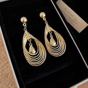 Detail view of gold-plated layered teardrop earrings with a hollow ring design and polished finish