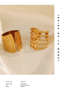 Detailed macro of 18K gold-plated geometric wide band and boho layered ring on silk