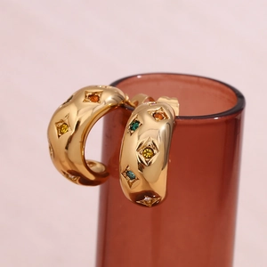 Macro view of gold plated hoop earrings with colorful zircon stars on glass rim