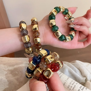 Detail of colorful acrylic beaded bracelets with glitter resin and gold metal beads