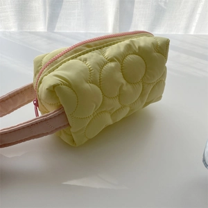 Detailed view of yellow quilted floral makeup bag with pink contrast zipper and handle