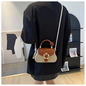 Détail du sac élégant en paille tressée avec fermoir fleur dorée et bandoulière en corde