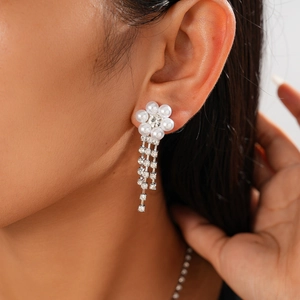 Close-up of floral drop earrings with white pearls and sparkling rhinestone tassels