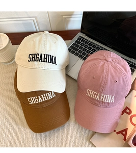 Close-up of three cotton baseball caps in beige, brown and pink with letter embroidery